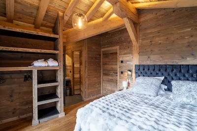 Chalet Verbier - Bardage e Rovere | Camera di uno chalet di prestigio interamente in legno antico: pareti, soffitto mansardato e cabina armadio su misura in Bardage marrone/beige, con travatura a vista in abete di recupero. Pavimento in rovere dai toni caldi, colore a progetto