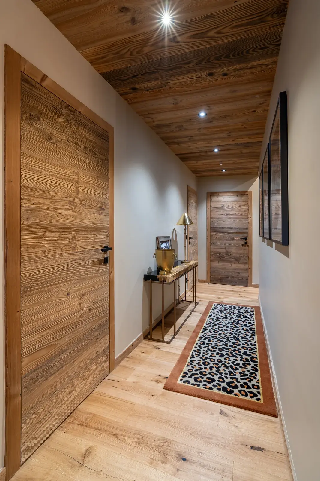 Corridoio di uno chalet con tre blocchi porta in legno antico a doghe verticali, soffitto in legno antico e parquet in rovere